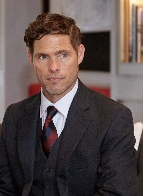 Alex Reece in a formal suit as a senior professional character